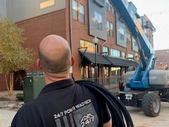 Man with hose over shoulder by commercial building