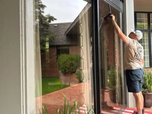 Man cleaning large window with squeegee