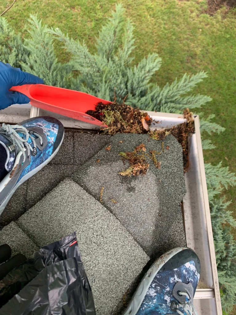 person on roof in oklahoma city cleaning gutters
